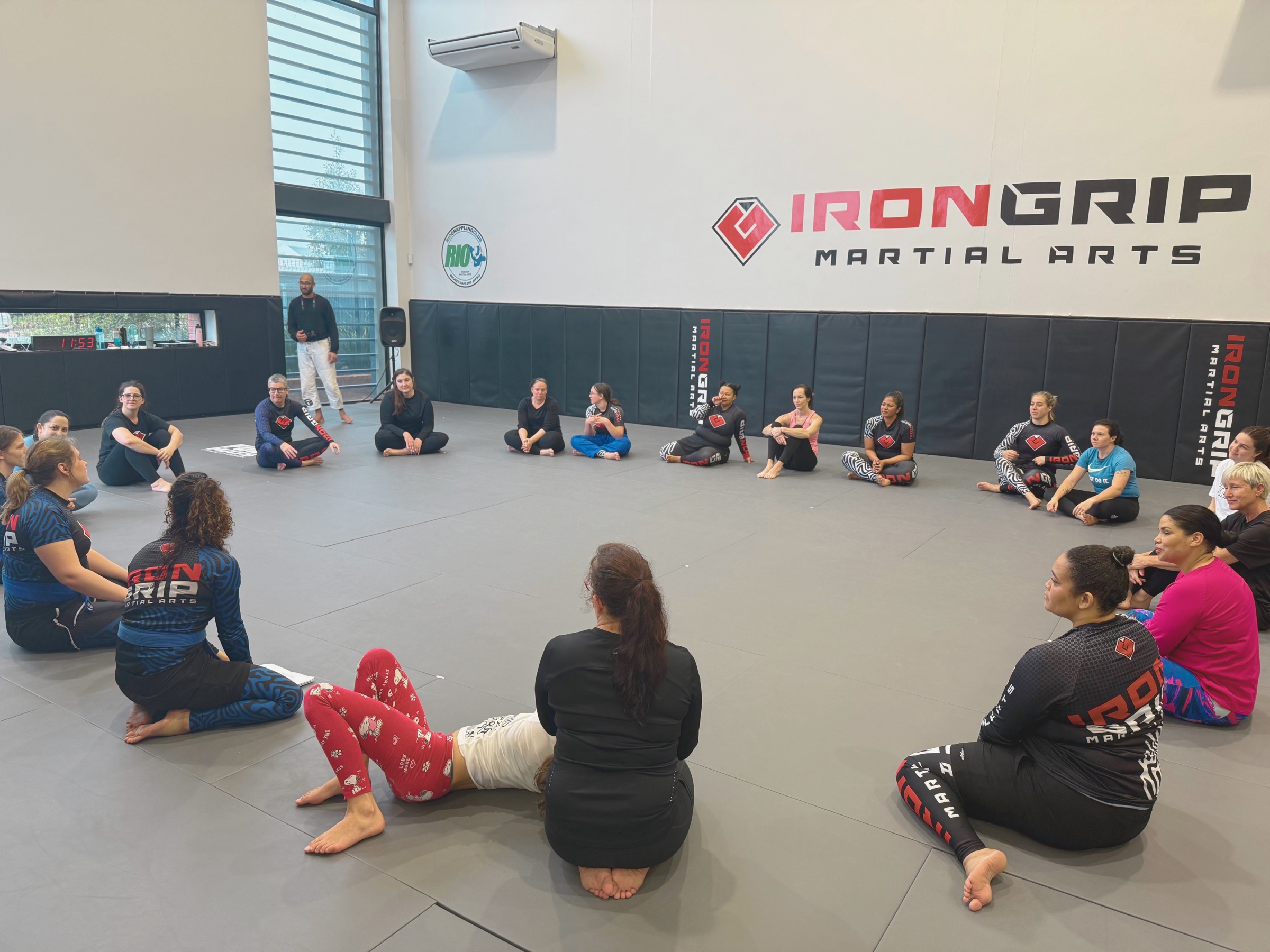 Women sitting together in a circle on the Iron Grip mats during a previous workshop