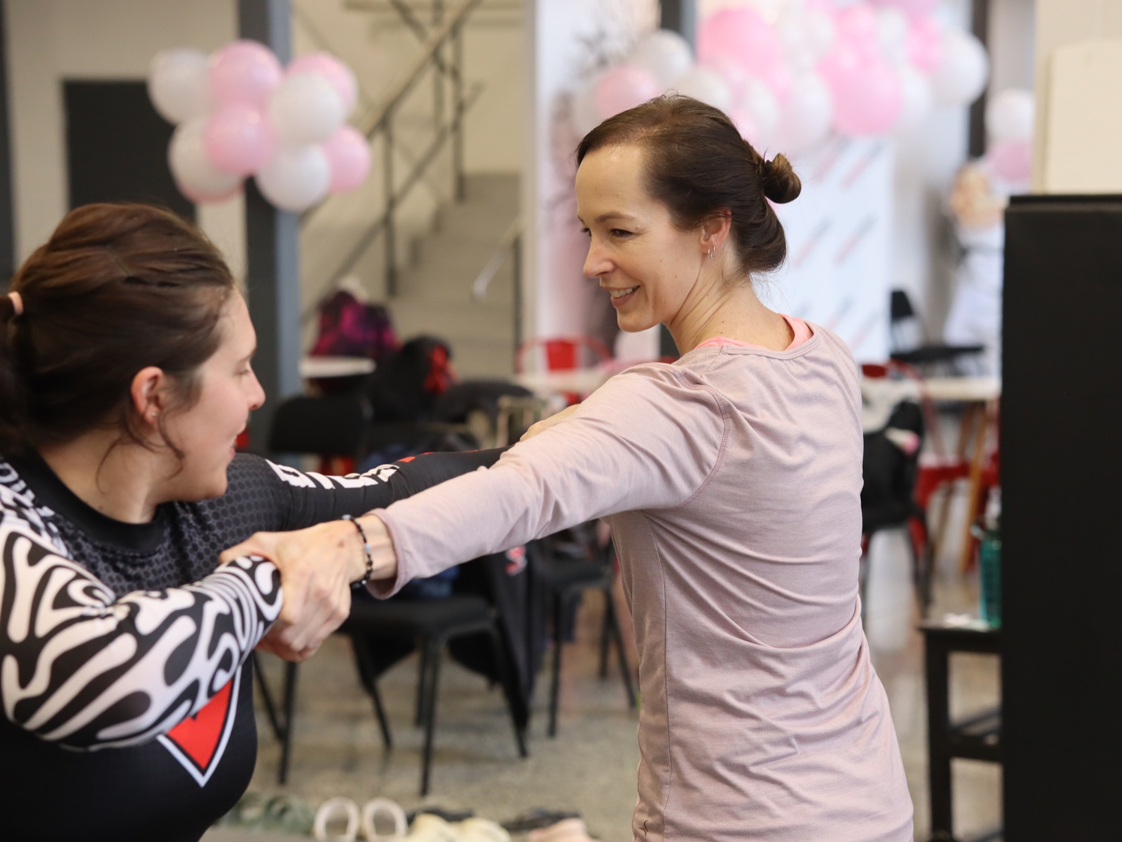 A woman smiles as she practises a movement with an Iron Grip coach